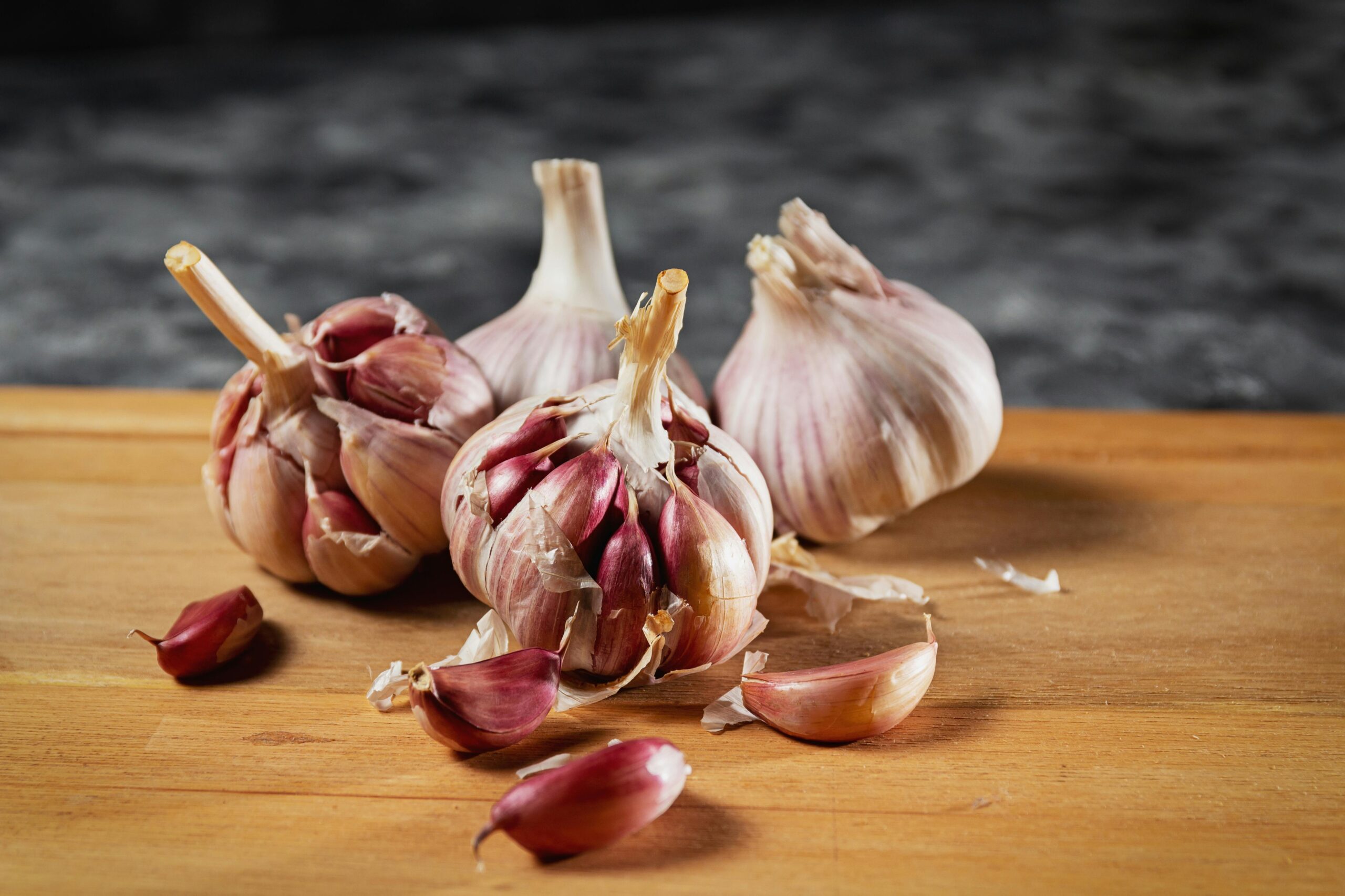 Close-up of fresh garlic bulbs and cloves on a wooden cutting board.
