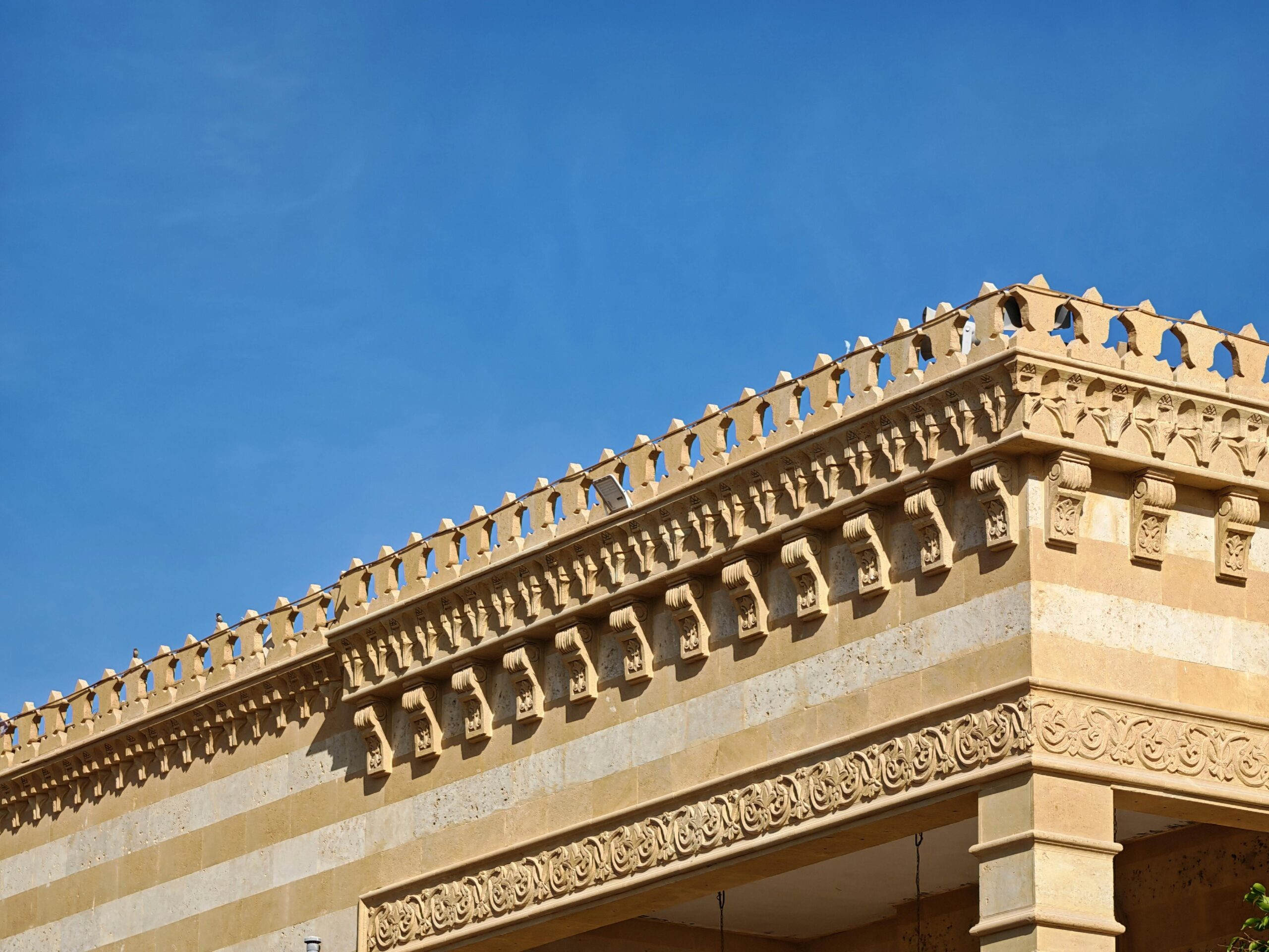 Corner view of a historic building with intricate carvings against a clear blue sky.